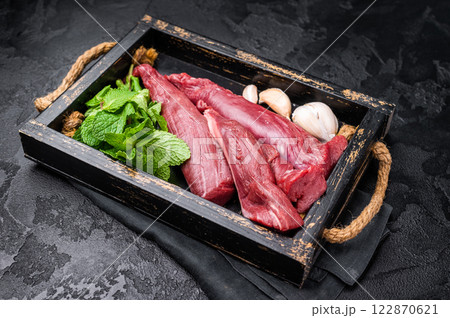 Mutton tenderloin fillet meat, raw lamb in wooden tray with herbs. black background. top view 122870621