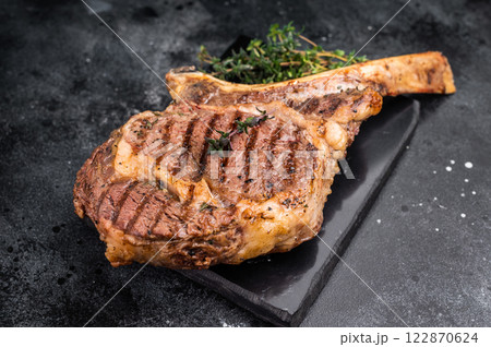 BBQ Grilled Tomahawk beef steak, cooked rib eye with bone on marble board. black background. top view 122870624