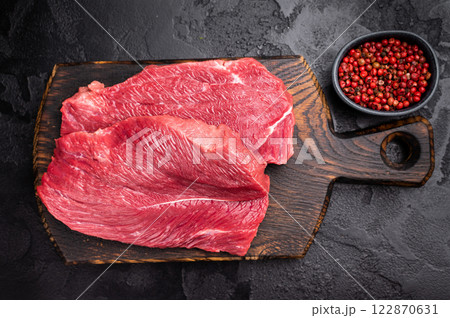 Raw Boar meat steak, uncooked Game Meat on cutting board. black background. top view Raw Boar meat steak, uncooked Game Meat on cutting board. black background. top view 122870631