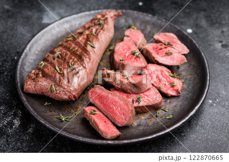 Grilled lamb mutoon sliced steak, tenderloin fillet meat. black background. top view Grilled lamb mutoon sliced steak, tenderloin fillet meat. black background. top view 122870665