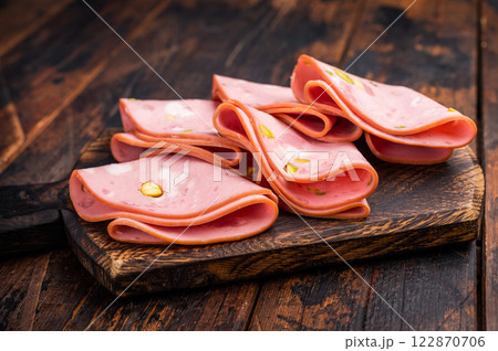Italian Mortadella sausage slices with pistachios on wooden cutting board. wooden background. top view 122870706