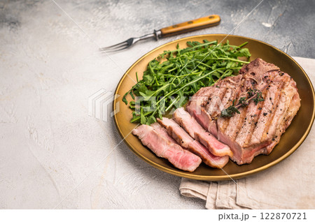 Roasted BBQ pork neck meat steak on plate with salad. grey background. top view 122870721