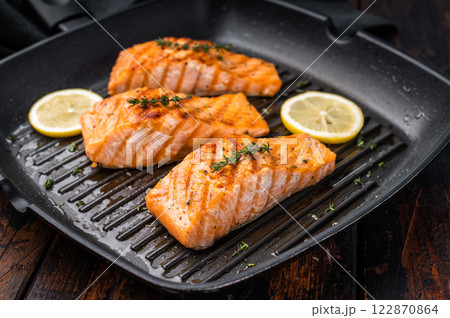 Pan fried salmon fillet steaks with thyme and lemon, fresh fish. wooden background. top view Pan fried salmon fillet steaks with thyme and lemon, fresh fish. wooden background. top view 122870864