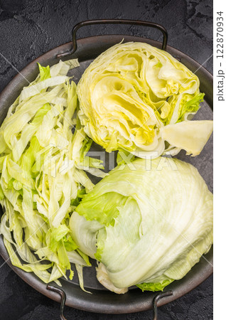 Fresh raw iceberg lettuce salad cut leaves. black background. top view Fresh raw iceberg lettuce salad cut leaves. black background. top view 122870934