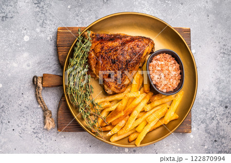 BBQ roast chicken thigh with french fry on a plate, poultry meat. grey background. top view 122870994