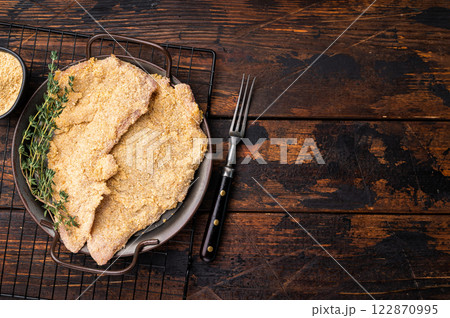 Viennese breaded raw Schnitzel steak on a tray. wooden background. top view 122870995