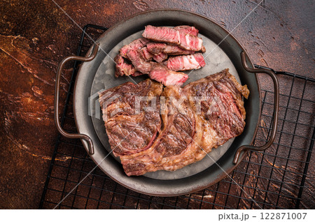 BBQ fried and sliced Chuck eye roll steak in a steel tray, prime beef meat. brown background. top view 122871007