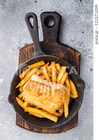 British fish and chips with fried cod fillet and French fry potato in skillet. grey background. top view 122871099