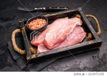 Raw pork chop fillet steaks in a wooden tray. black background. top view Raw pork chop fillet steaks in a wooden tray. black background. top view 122871105