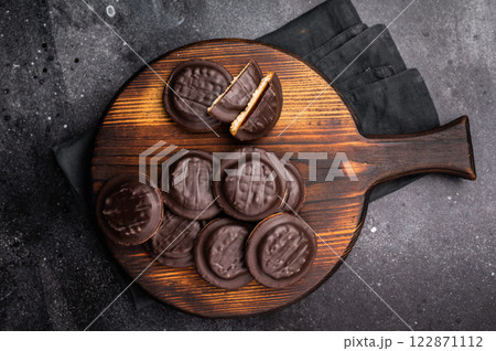 Jaffa Cookies covered with chocolate and filled with jam on wooden board. black background. top view 122871112