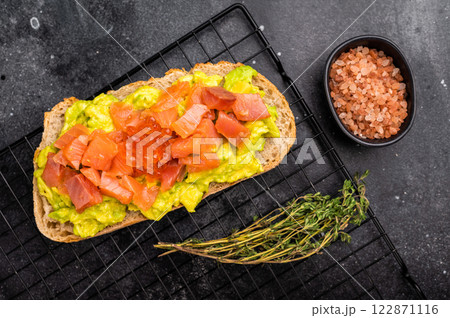 Toast with salty salmon, trout slices, avocado and red caviar. black background. top view Toast with salty salmon, trout slices, avocado and red caviar. black background. top view 122871116