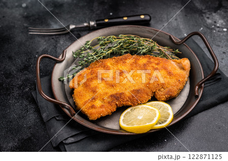 German Wiener schnitzel steak, breaded pork fillet meat. black background. top view 122871125