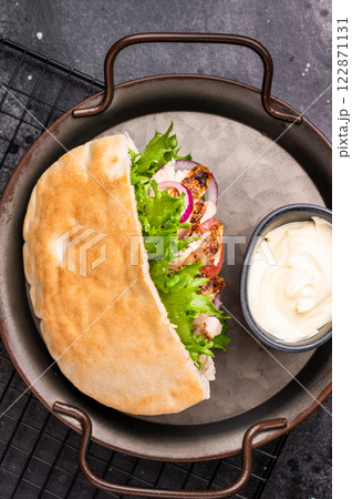 Gyros with grilled chicken meat, salad, tomato, onion, tzatziki in pita bread. black background. top view Gyros with grilled chicken meat, salad, tomato, onion, tzatziki in pita bread. black background. top view 122871131