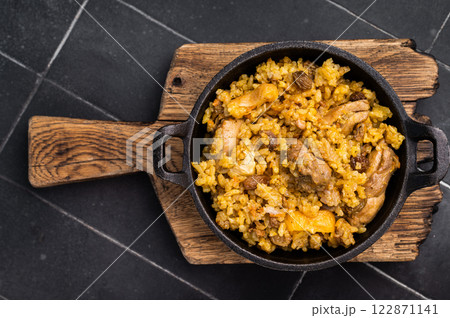 Pilaf with beef and lamb meat, vegetables in a skillet. black background. top view 122871141