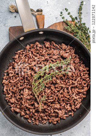 Frying Pan with fried mince beef meat, fresh cooked forcemeat. grey background. top view Frying Pan with fried mince beef meat, fresh cooked forcemeat. grey background. top view 122871142