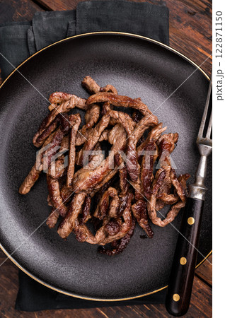 BBQ Fried beef tender strips, sliced steak in a plate. wooden background. top view BBQ Fried beef tender strips, sliced steak in a plate. wooden background. top view 122871150