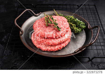 Stack of Raw meat patties, cutlets, chopped meat for burgers in stell tray with herbs. black background. top view Stack of Raw meat patties, cutlets, chopped meat for burgers in stell tray with herbs. black background. top view 122871278