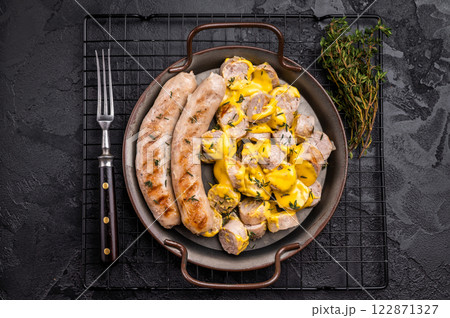 Currywurst sliced Sausages with curry sauce, wurst in steel plate. black background. top view Currywurst sliced Sausages with curry sauce, wurst in steel plate. black background. top view 122871327