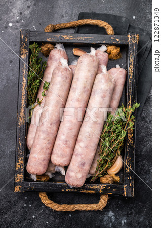 Raw Sausages with minced chicken and turkey meat with herbs in wooden tray. black background. top view 122871349