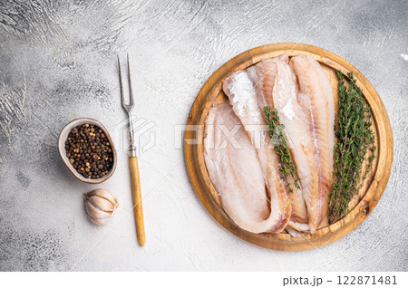 Fresh Raw Hake fish fillets, whitefish meat on a wooden board with herbs. white background. top view Fresh Raw Hake fish fillets, whitefish meat on a wooden board with herbs. white background. top view 122871481
