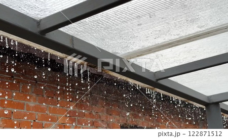 Heavy rain drumming on the transparent plexiglass roof. Beautiful rainy scene on summer day. Concept of tranquility nature scene. Close up Slow motion 122871512