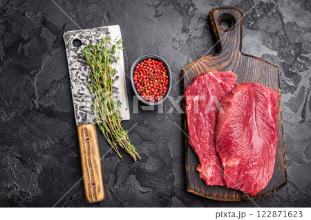 Raw Boar meat steak, uncooked Game Meat on cutting board. black background. top view Raw Boar meat steak, uncooked Game Meat on cutting board. black background. top view 122871623