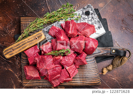 Diced Raw Boar meat, uncooked Game Meat on butcher cutting board. brown background. top view Diced Raw Boar meat, uncooked Game Meat on butcher cutting board. brown background. top view 122871628