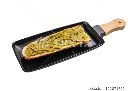 Delicious green pesto spread on toasted bread, garnished with herbs isolated on white background 122871731