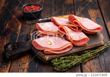 Italian Mortadella sausage slices with pistachios on wooden cutting board. wooden background. top view 122871809