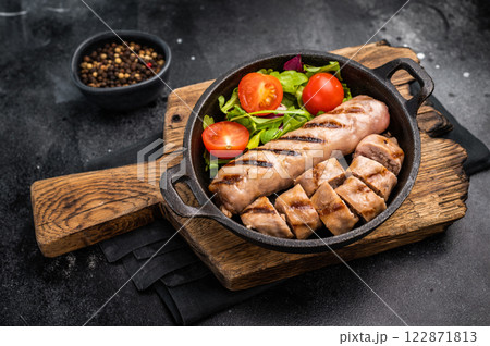 Dinner with Salad and grilled pork sausages in a skillet. black background. top view 122871813