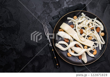 Smoked Traditional Chechil white cheese on a plate with nuts, black background. 122871819