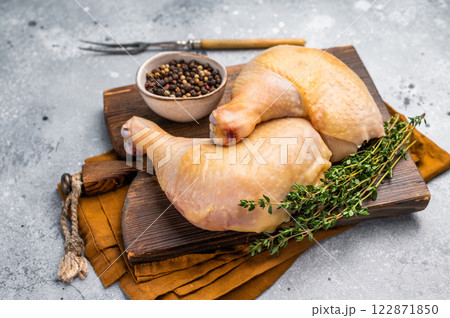 Raw chicken legs on wooden cutting board, eco poultry meat on gray background, top view Raw chicken legs on wooden cutting board, eco poultry meat on gray background, top view 122871850