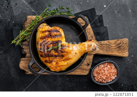 Grilled chicken leg or quarter in a skillet, roasted poultry meat on black background, top view 122871851