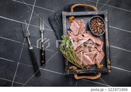 Cooked boiled sliced beef meat in wooden tray. black background. top view Cooked boiled sliced beef meat in wooden tray. black background. top view 122871866
