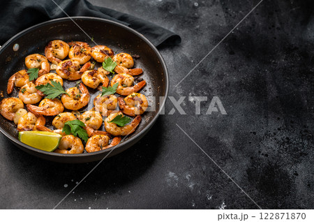 Fried Shrimps Prawns with garlic and butter in a skillet. Black background. Top view Fried Shrimps Prawns with garlic and butter in a skillet. Black background. Top view 122871870