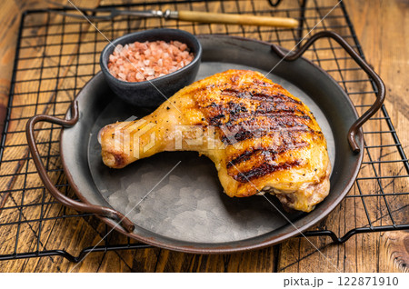 Grilled chicken leg or quarter in a skillet, roasted poultry meat on black background, top view. Grilled chicken leg or quarter in a skillet, roasted poultry meat on black background, top view. 122871910