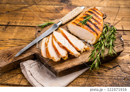 Grilled and sliced Chicken breasts on cutting board, grilled poultry meat, top view, wooden background. 122871916