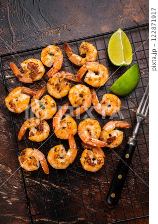 Grilled Shrimps Prawns with garlic on a rack. Brown background. Top view 122871917