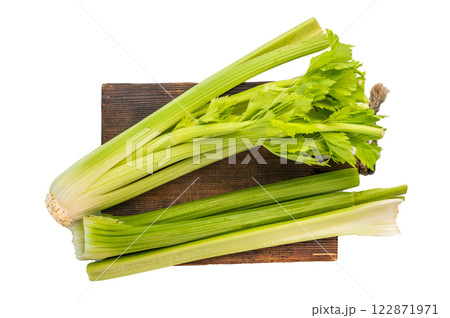 Raw uncooked celery sticks on wooden cutting board isolated on white background, top view Raw uncooked celery sticks on wooden cutting board isolated on white background, top view 122871971