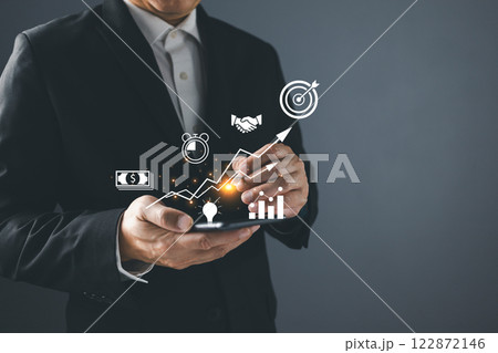 Businessman holding a smartphone with icon business and network connection on modern virtual interface from digital smartphone.Use technology to plan strategy to success goals and growth. e-commerce. Businessman holding a smartphone with icon business and network connection on modern virtual interface from digital smartphone.Use technology to plan strategy to success goals and growth. e-commerce. 122872146