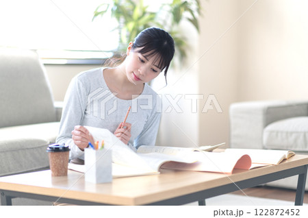 リビングで一人で勉強する若い女性 リビングで一人で勉強する若い女性 122872452
