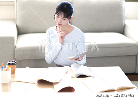 リビングで一人で勉強する若い女性 リビングで一人で勉強する若い女性 122872462