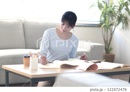 リビングで一人で勉強する若い女性 リビングで一人で勉強する若い女性 122872476
