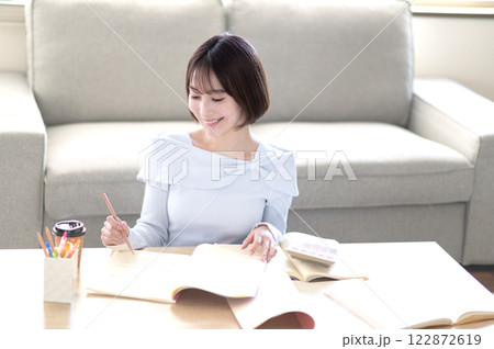 リビングで一人で勉強する若い女性 リビングで一人で勉強する若い女性 122872619