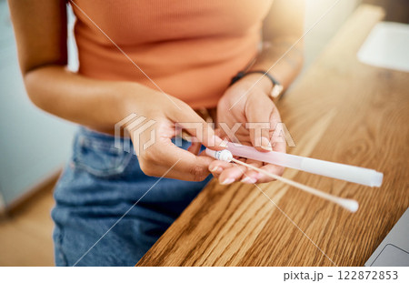 Woman with kit for covid test in hand at desk, to analyse results and get diagnosis for wellness in home. Woman with cotton swab and tube at table, do PCR test for symptoms or sign of coronavirus 122872853