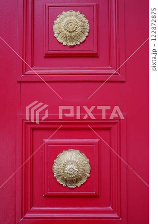 Beautiful red doors with metal decorations. The color of luxury. The aesthetics of red and bronze 122872875
