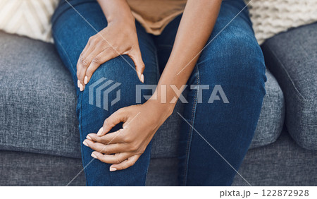 Black woman, hands and knee injury pain for person on house living room sofa or home interior lounge. Zoom on healthcare, wellness or medical surgery burnout, stress and legs muscle accident on couch 122872928