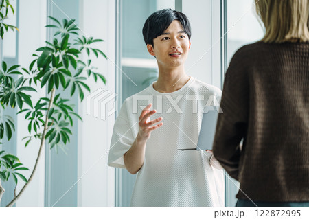 同僚と話すカジュアル服を着た若いエンジニア 同僚と話すカジュアル服を着た若いエンジニア 122872995