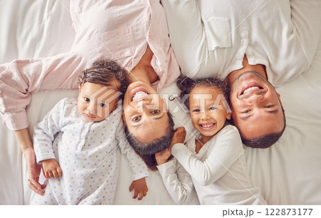Portrait of family home, kids and parents on bed for fun morning, relax lifestyle and happiness. Above of smile mom, happy dad and playful children together in bedroom for love, care and joy weekend 122873177