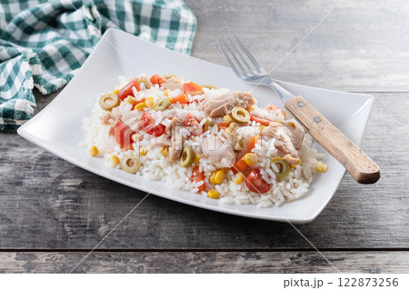 Rice salad with tomato, corn,olives and tuna on wooden table.  122873256
